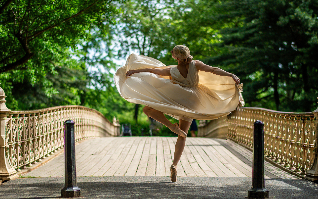 Девушка балерина в стойке на мосту