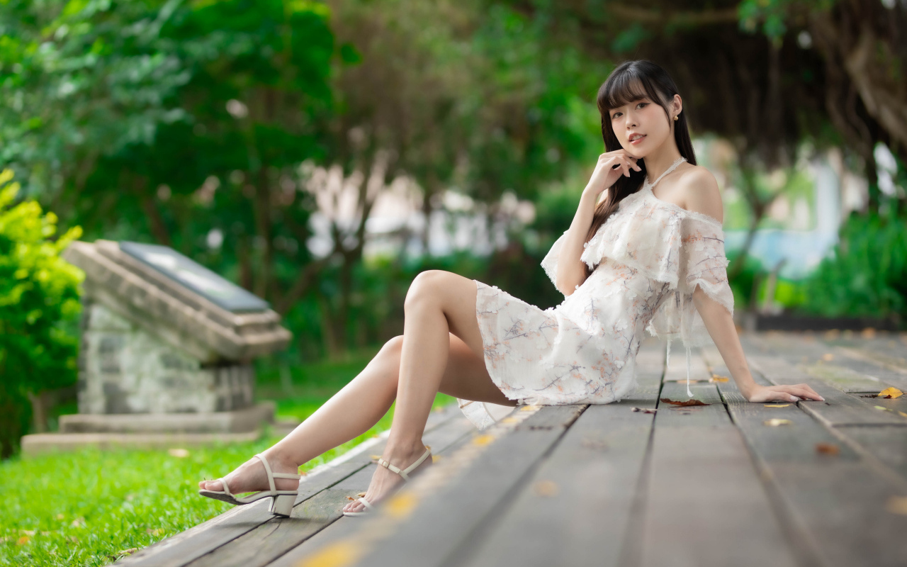 Симпатичная молодая азиатка сидит на деревянном покрытии