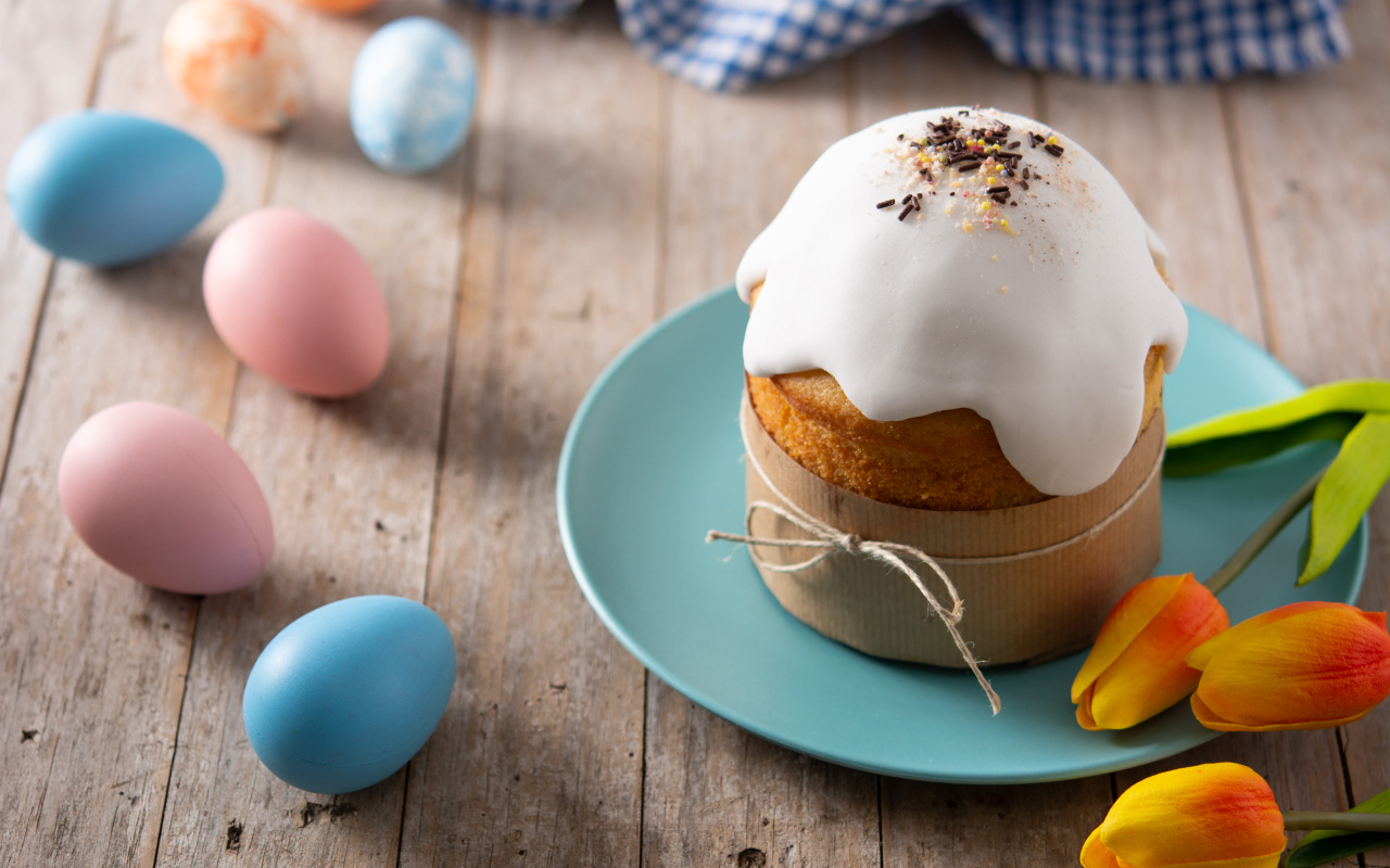 Кулич с крашеными яйцами и цветами на столе на Пасху