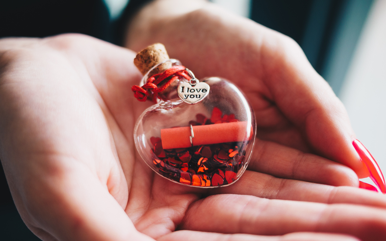 Ладони с маленький стеклянным сердечком