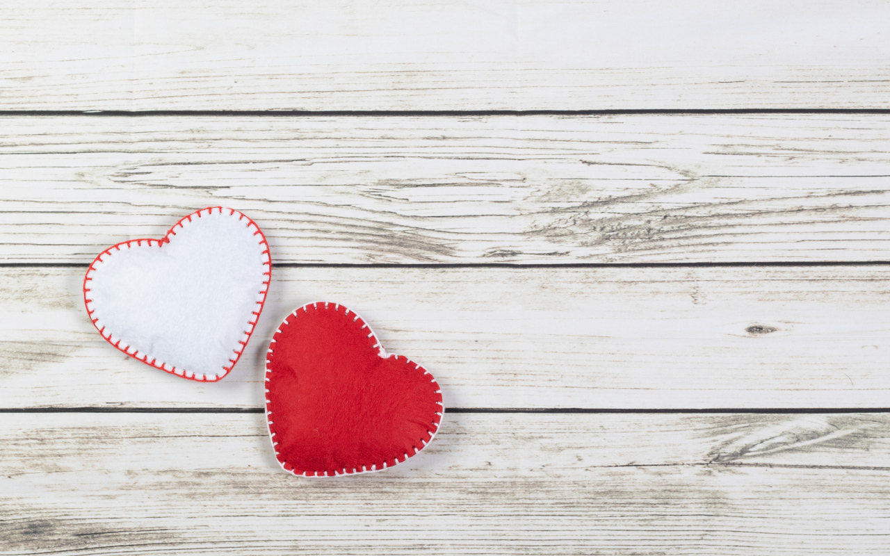 Белое и красное сшитое сердце на деревянном фоне