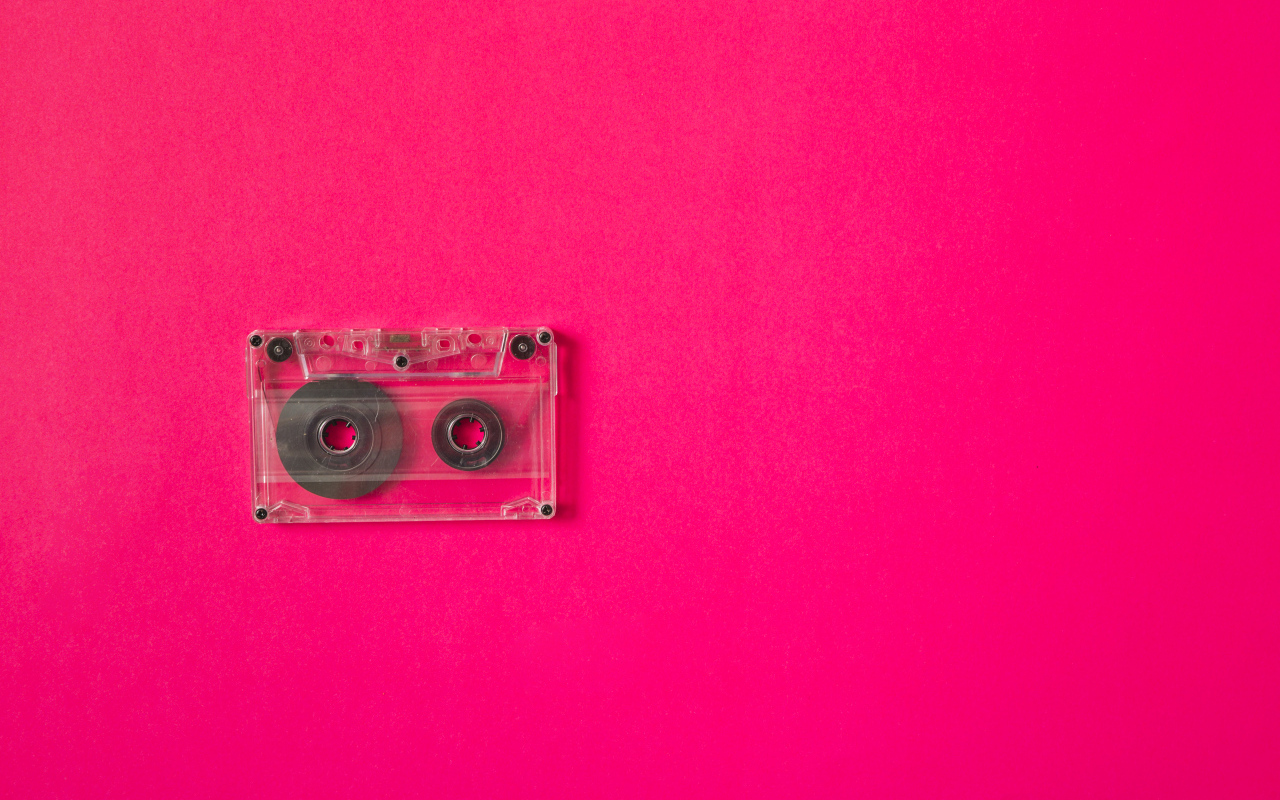 Маленькая магнитофонная кассета на розовом фоне