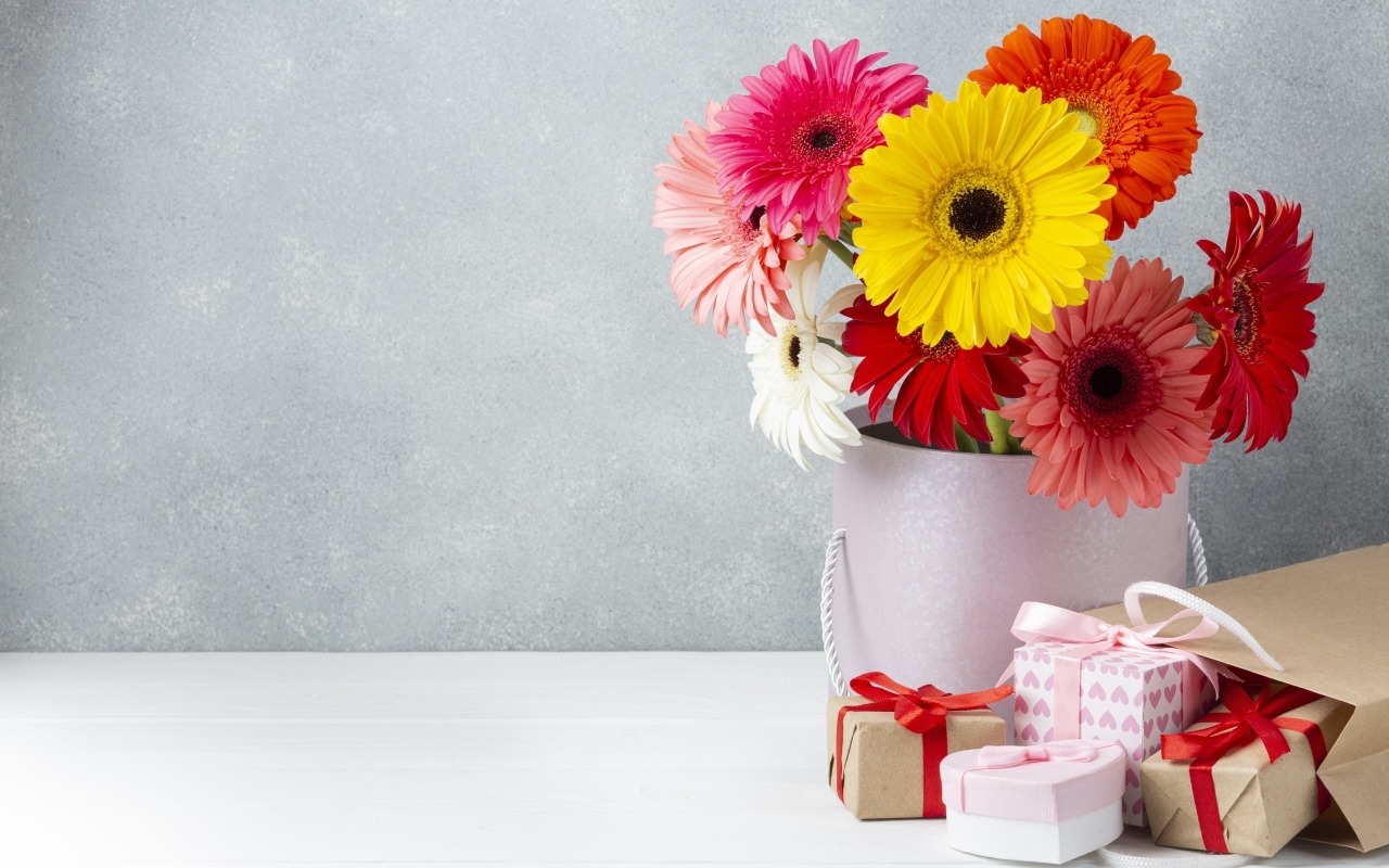 Букет разноцветных цветов герберы на столе с подарками