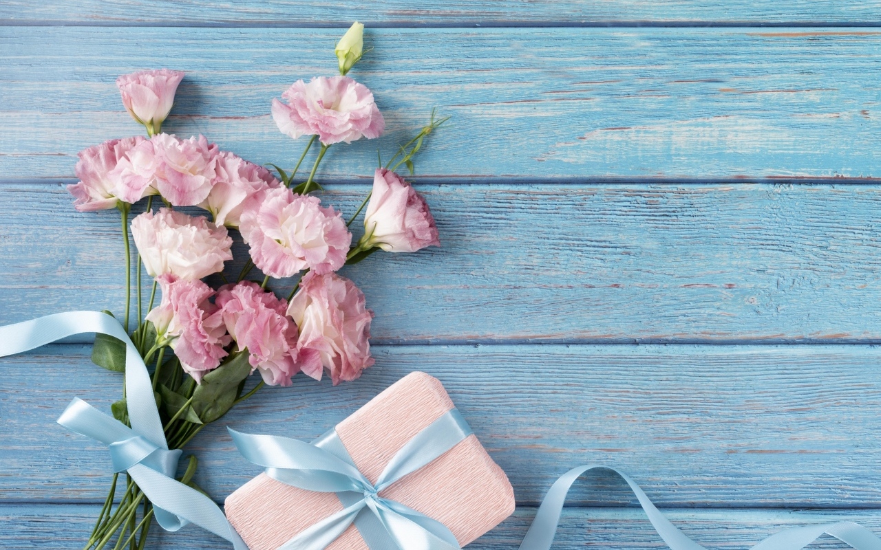 Букет розовых цветов эустомы с подарком на голубом столе