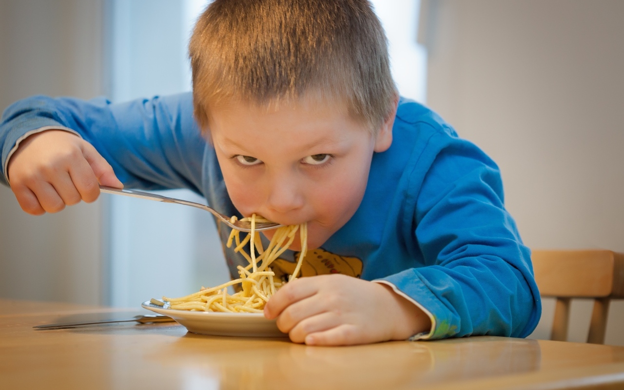 Маленький мальчик ест макароны