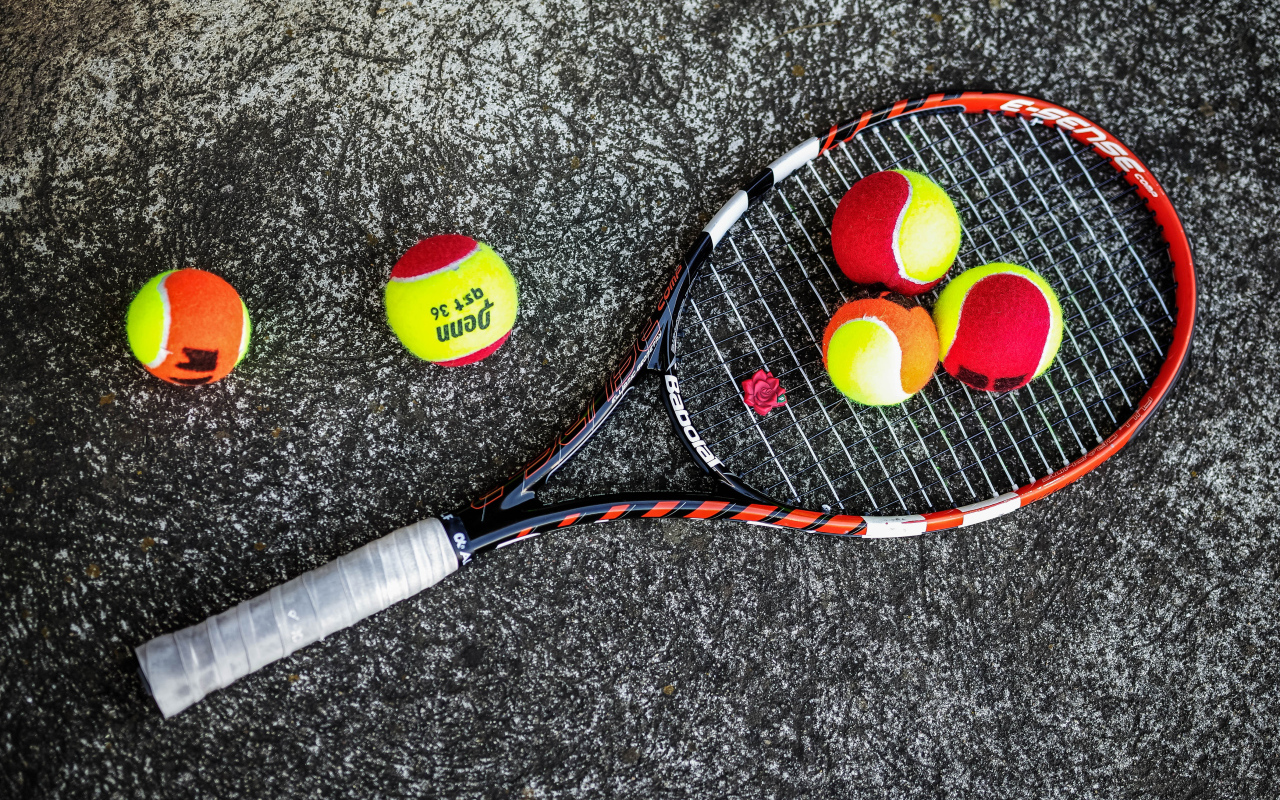 Ракетка и теннисные мячи на черном фоне