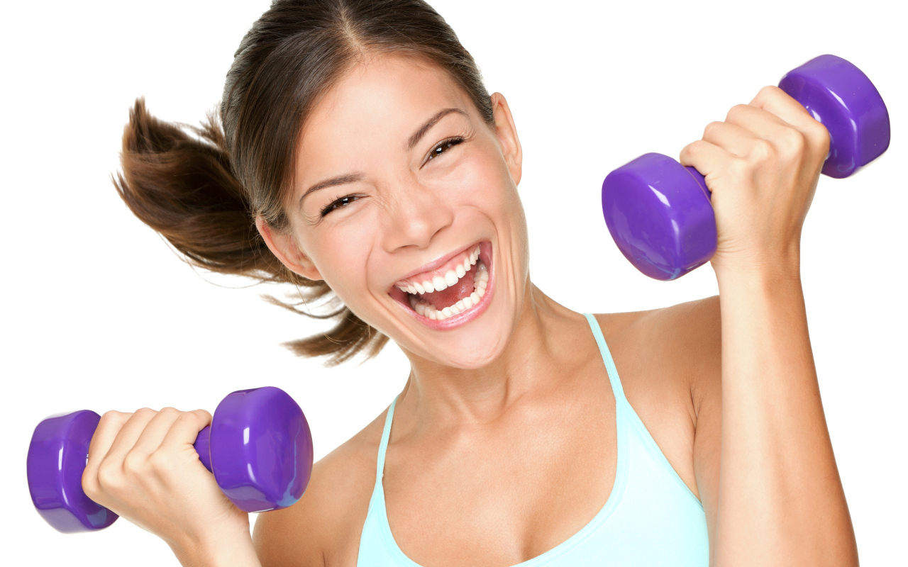 Веселая спортивная девушка с гантелями в руках