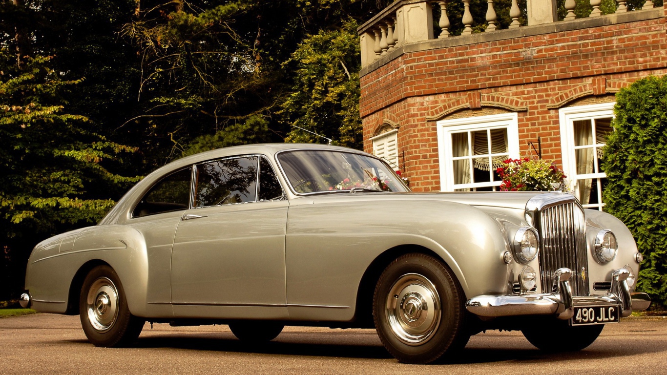 Белый автомобиль у кирпичного дома