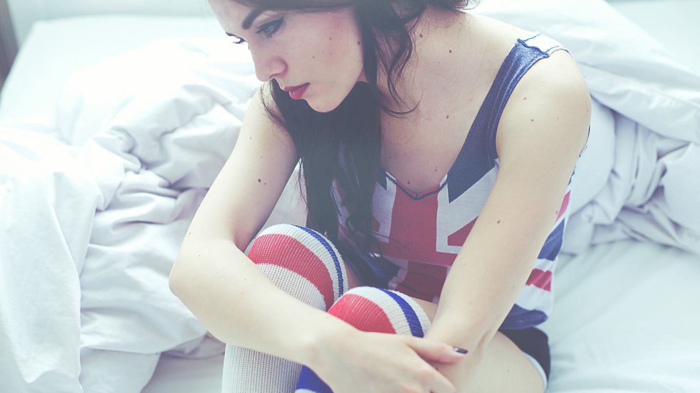 Девушка грустит на кровати