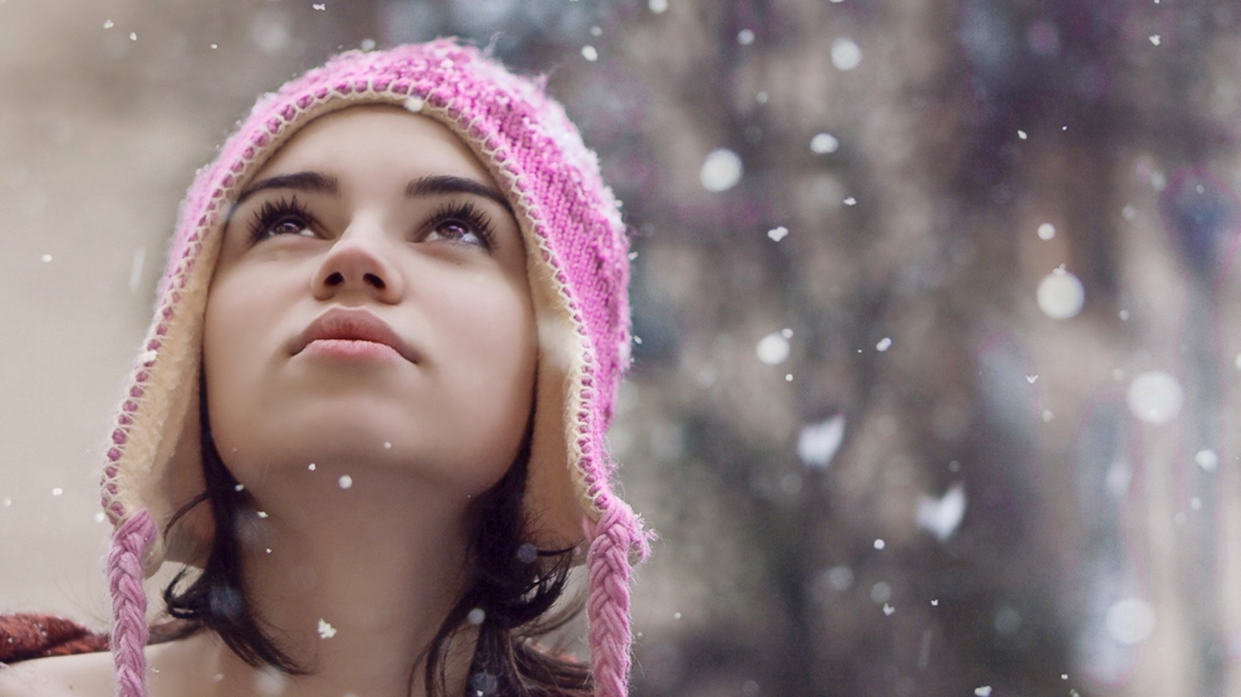 Девушка смотрит на падающий снег