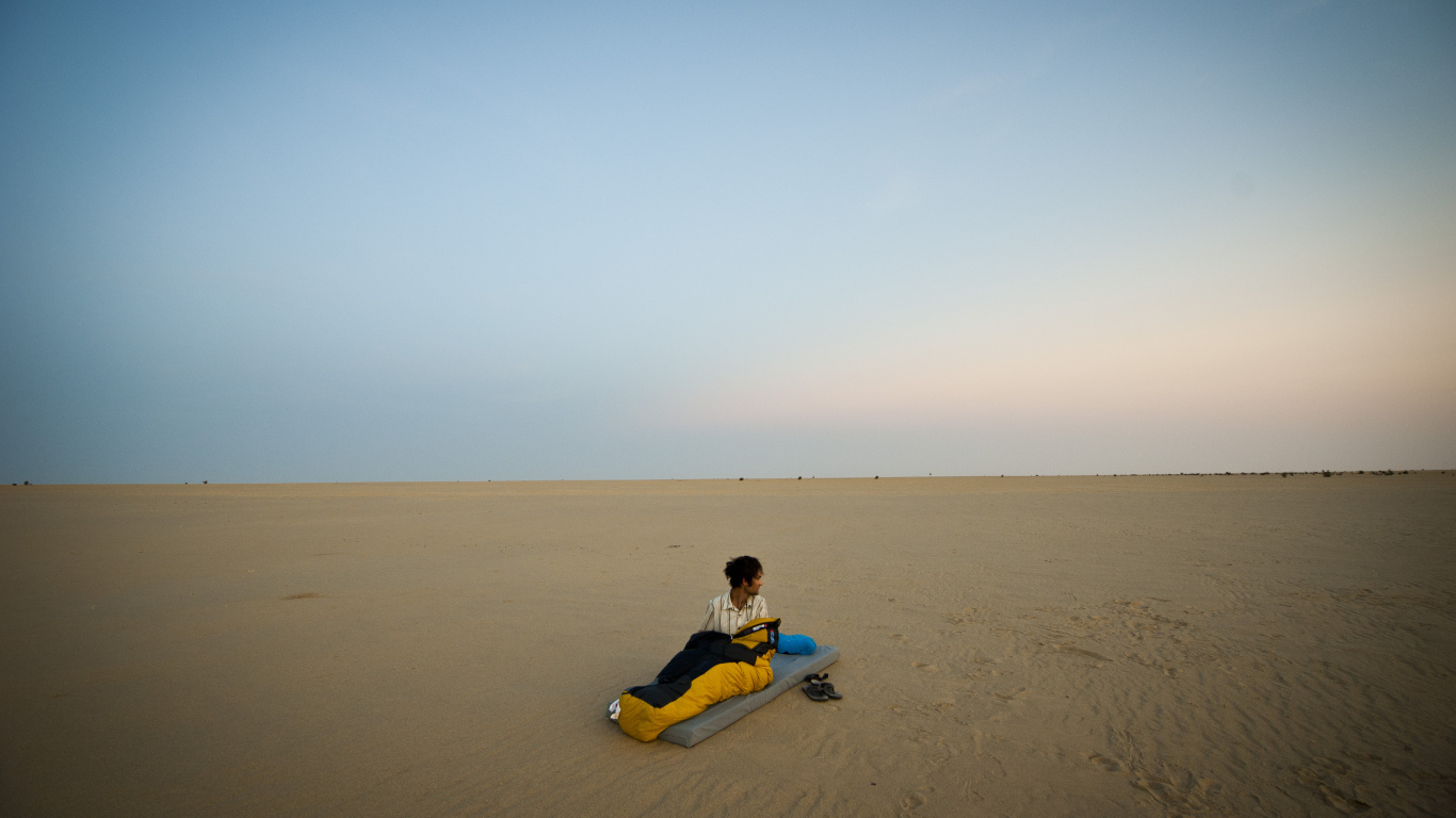 Мужчина на матрасе на пляже