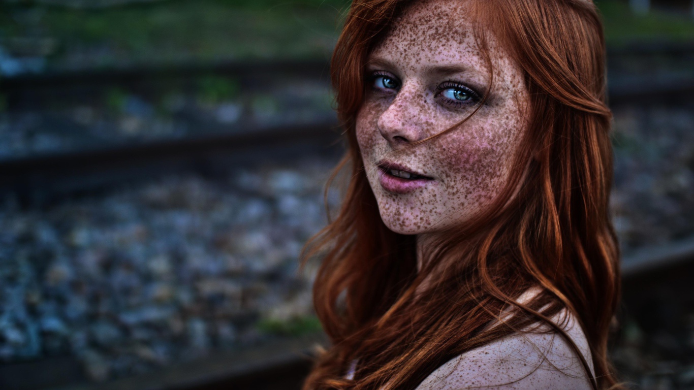 Девушка с веснушками на фоне рельс