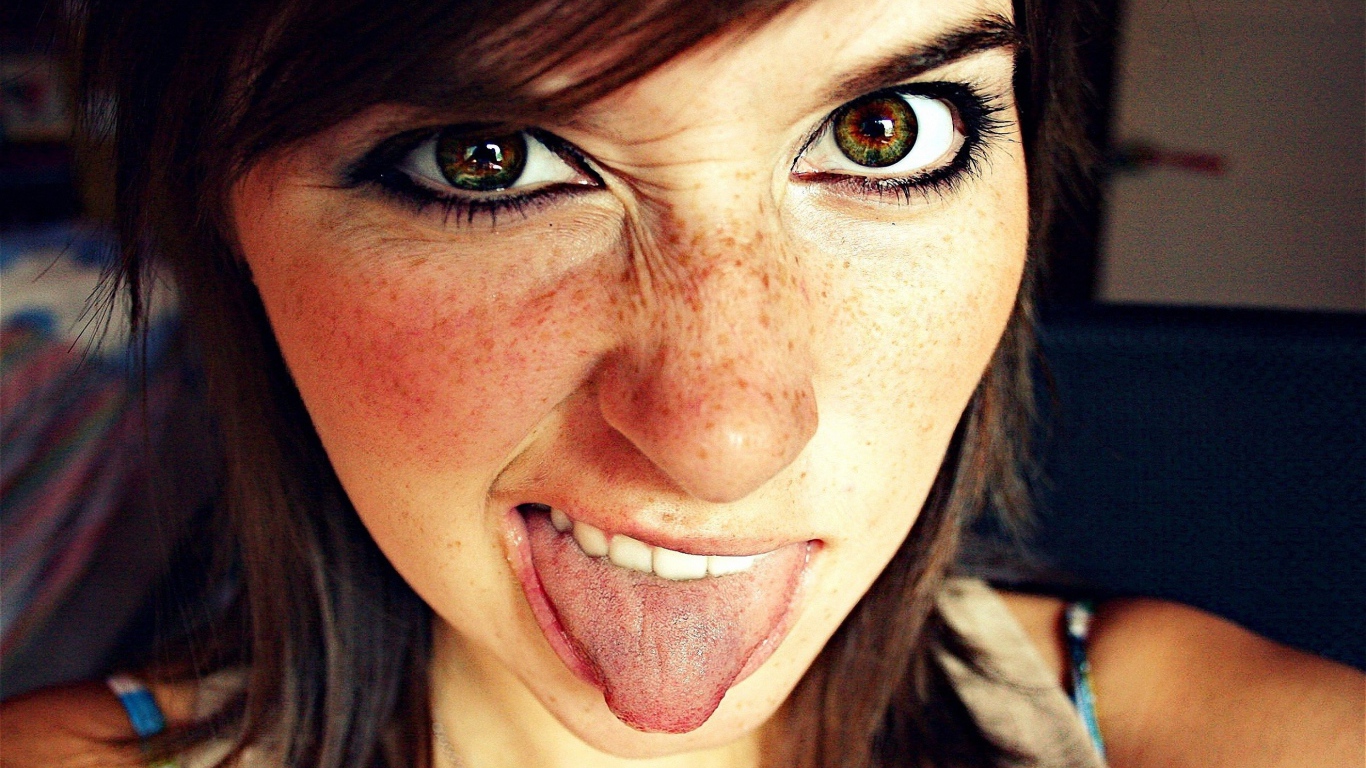 Девушка с веснушками показывает язык