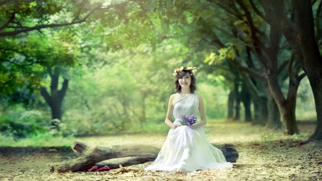 Девушка сидит на бревне