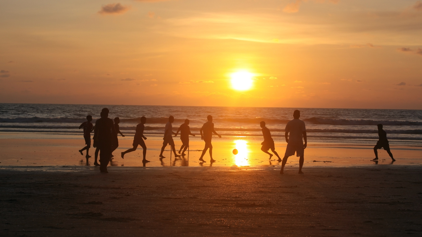 Парни играют в футбол на пляже в Гоа