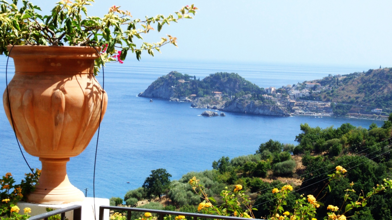 Кувшин с цветами на фоне залива на острове Сицилия, Италия