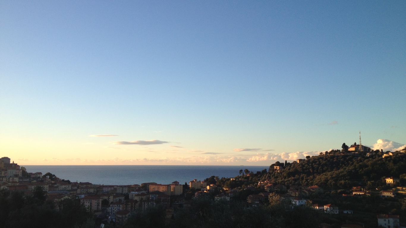 Закат над городом на курорте Империя, Италия