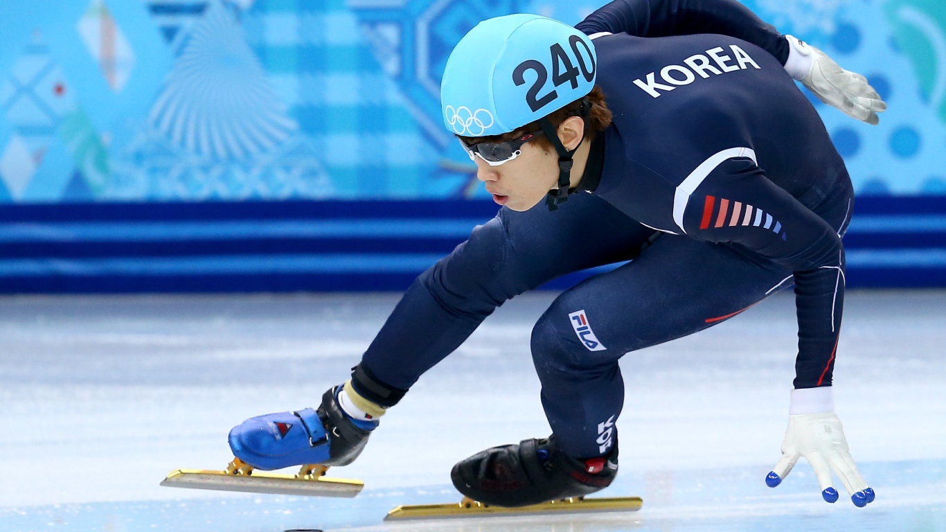 Спортсмен входит в поворот на соревнованиях по скоростному бегу на коньках на Олимпиаде в Сочи