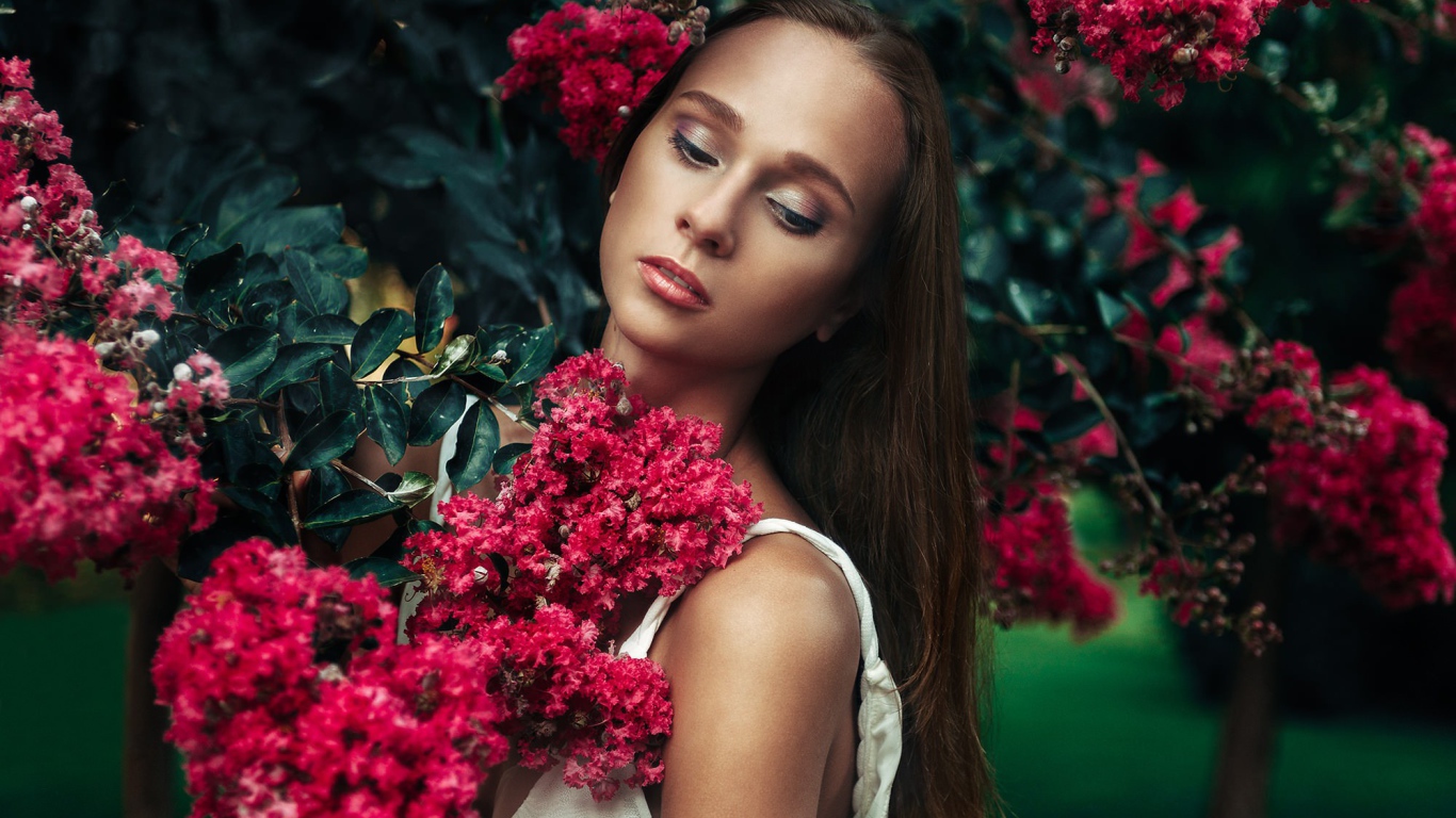 A girl among the branches of a blossoming tree