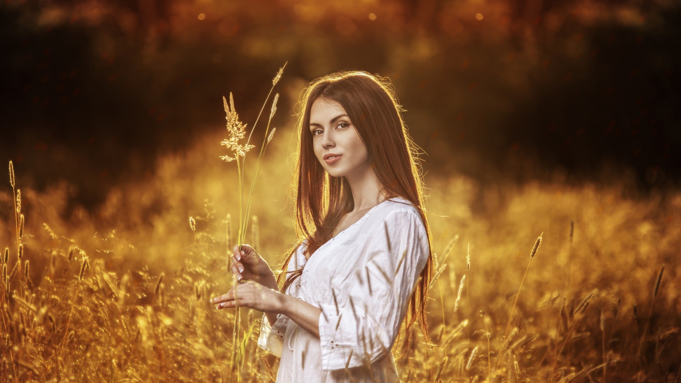 Девушка в белом платье держит в руке колоски