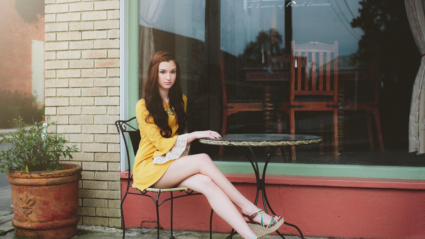 Девушка сидит за столиком уличного кафе