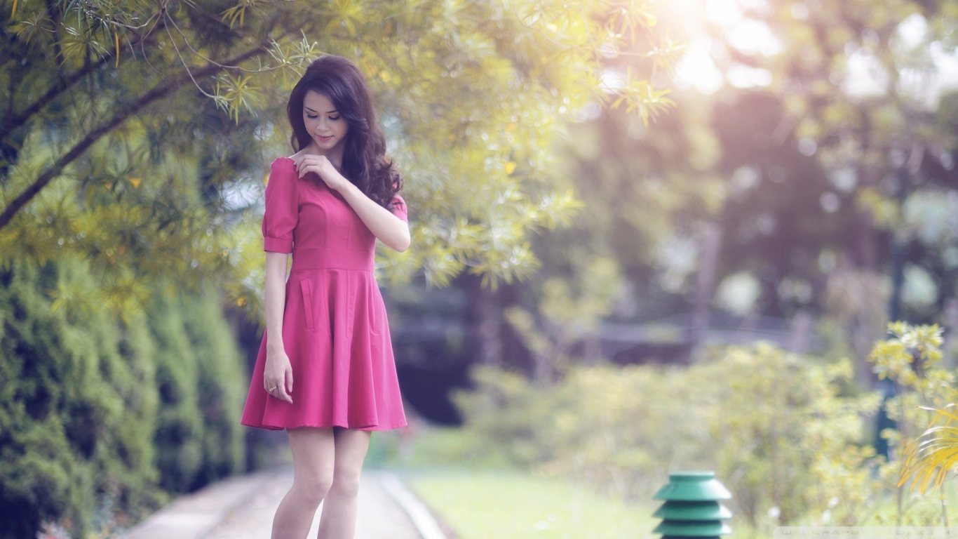Азиатка в красном платье гуляет в саду