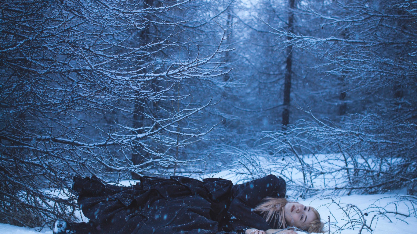 Блондинка лежит на снегу в лесу