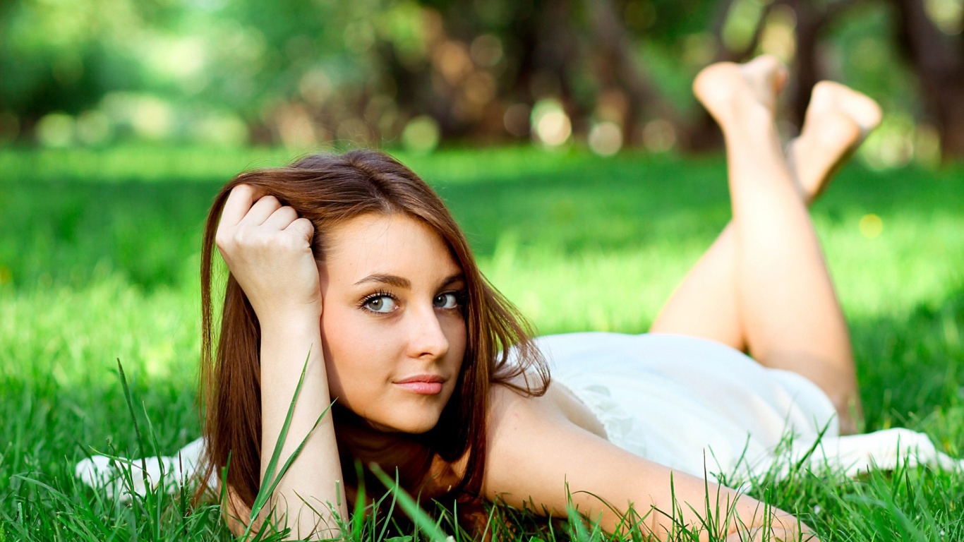 Беззаботная девушка лежит на зеленой траве