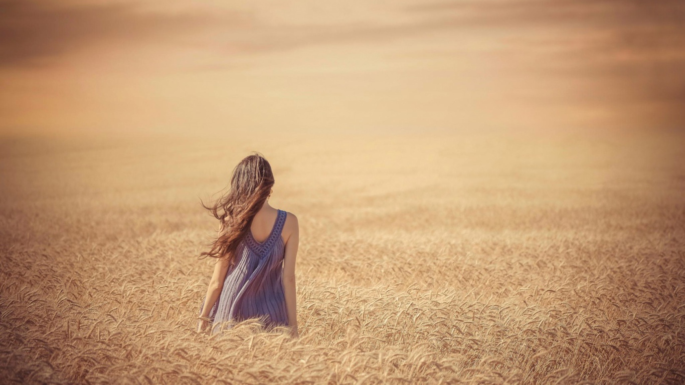 Девушка среди поля спелой пшеницы