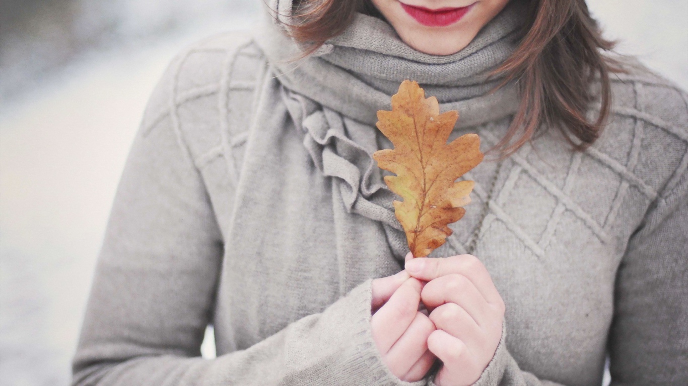 Девушка держит в руках желтый лист