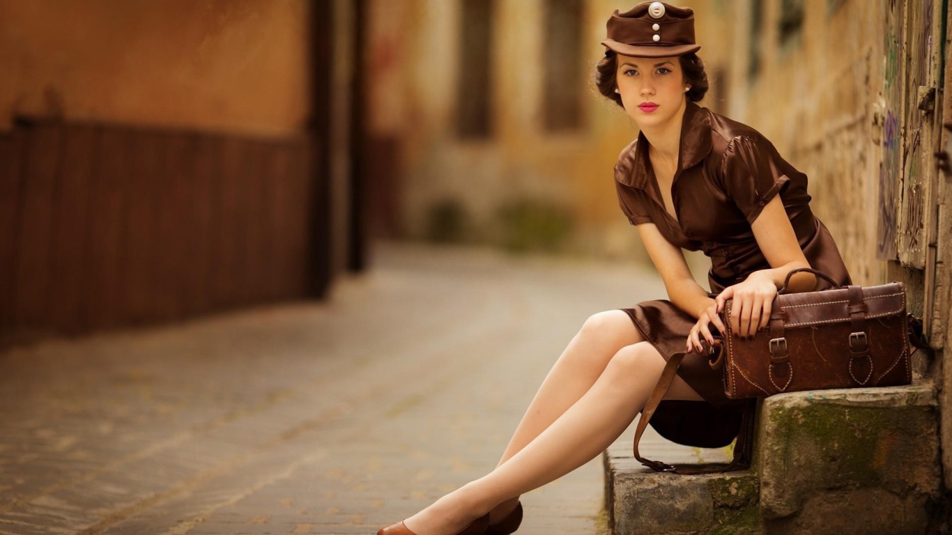 Девушка в коричневой одежде сидит у дороги