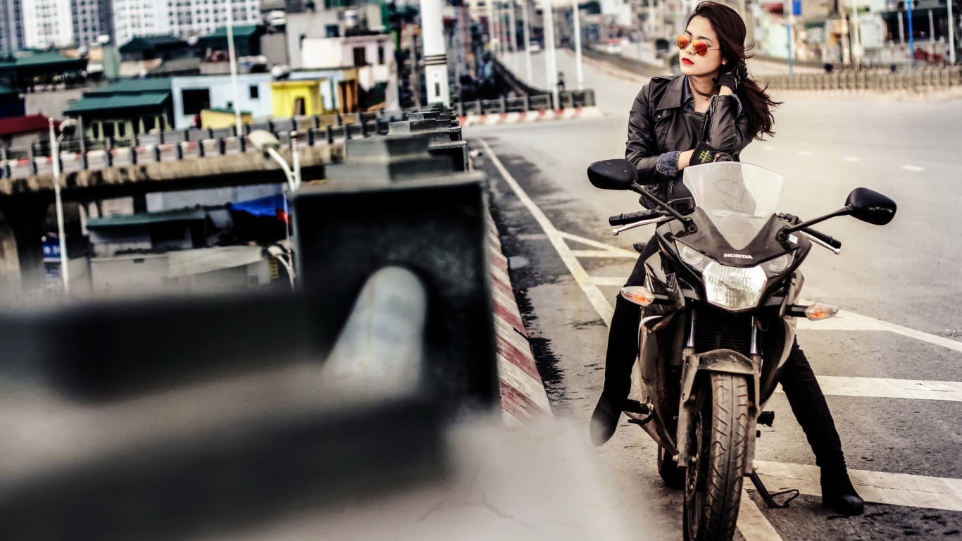 Девушка в темных очках сидит на мотоцикле