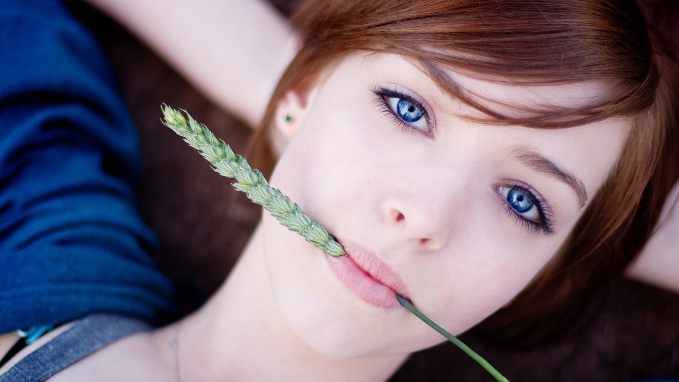 Зеленый колосок во рту у девушки