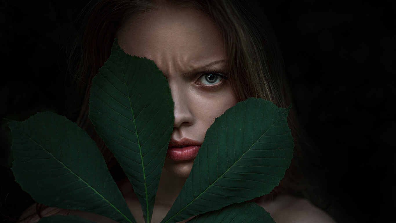 Девушка прикрыла лицо листьями каштана