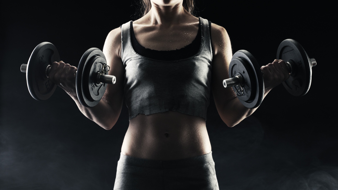 Спортивная девушка с гантелями в руках