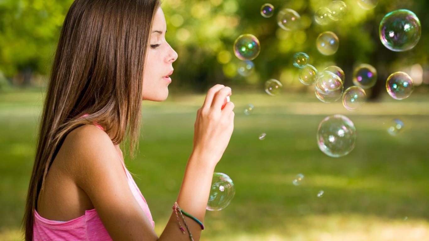 Девушка в розовой футболке запускает мыльные пузыри