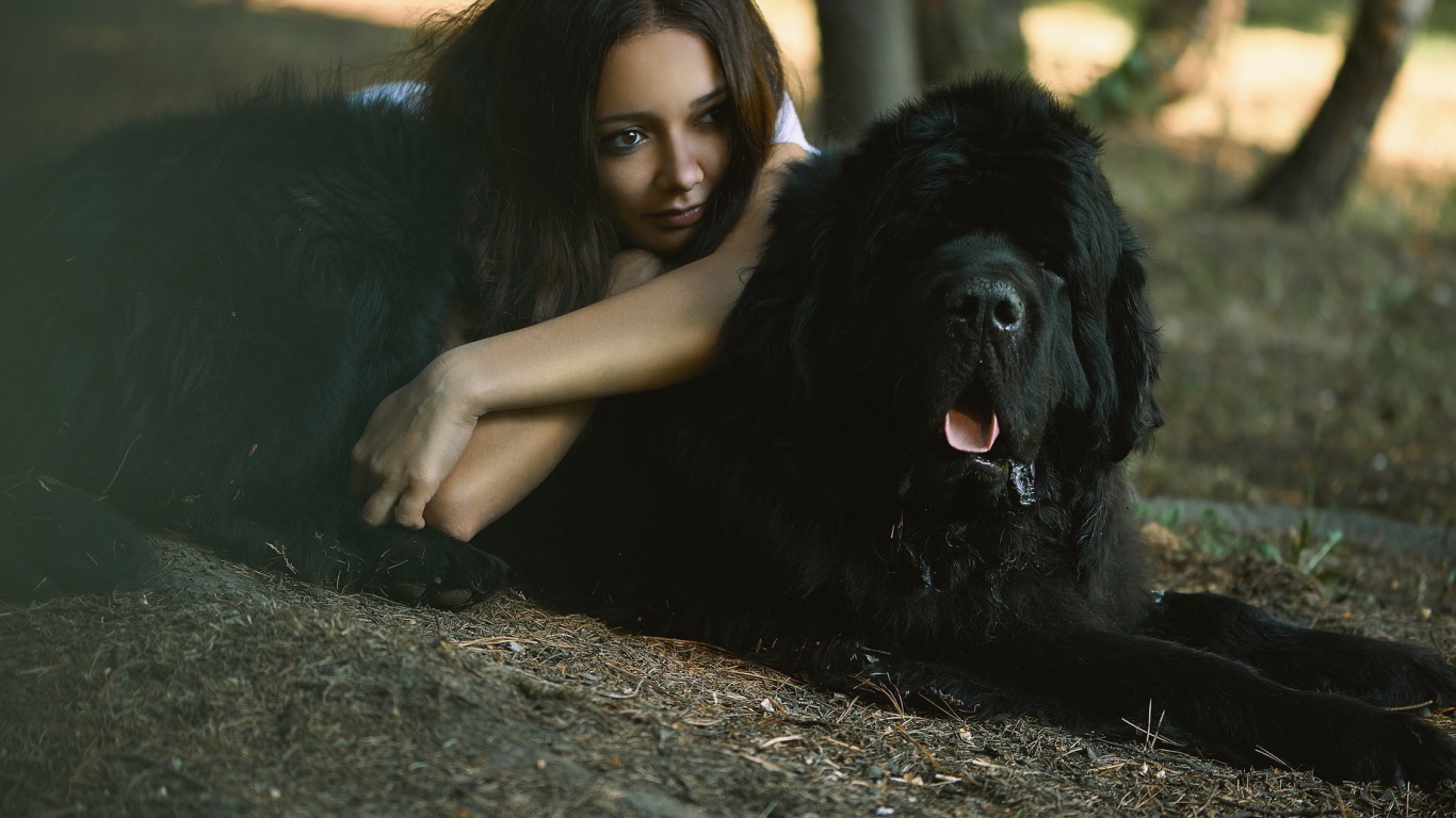 Девушка лежит на большой черной собаке