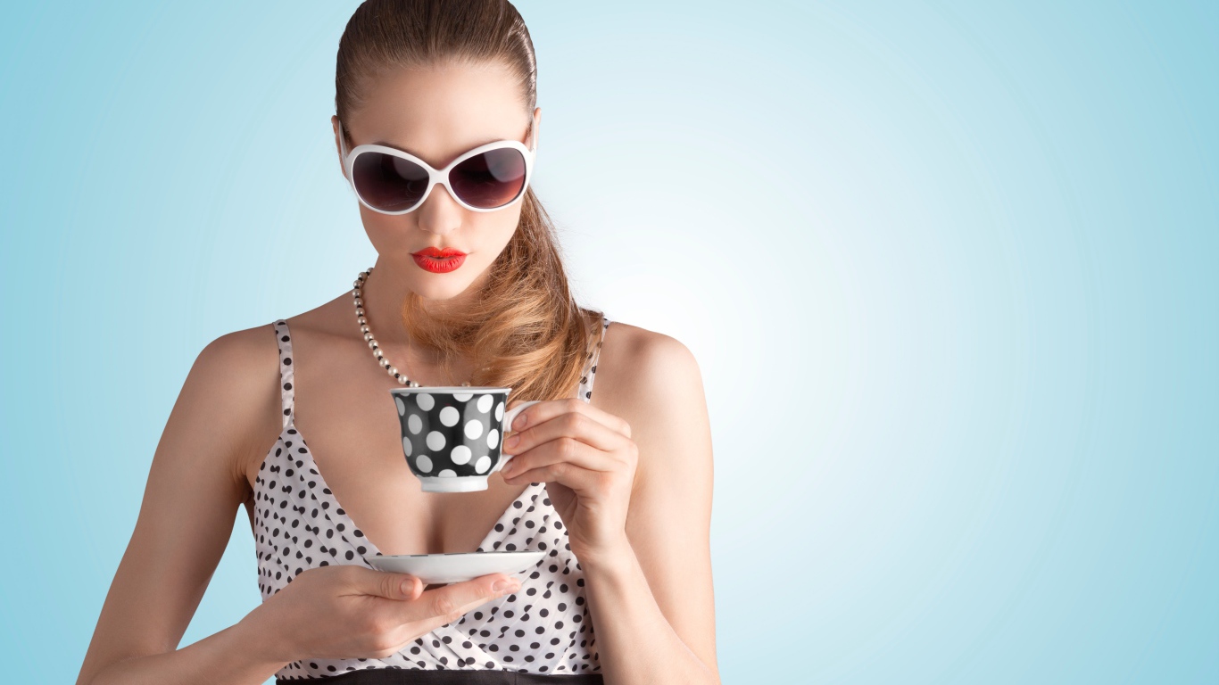 Модель в темных очках с чашкой на голубом фоне