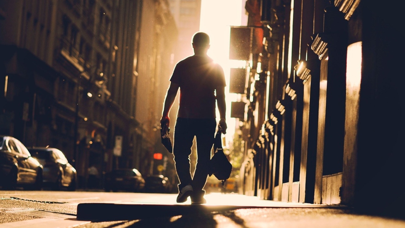 Мужчина идет по улице навстречу солнцу