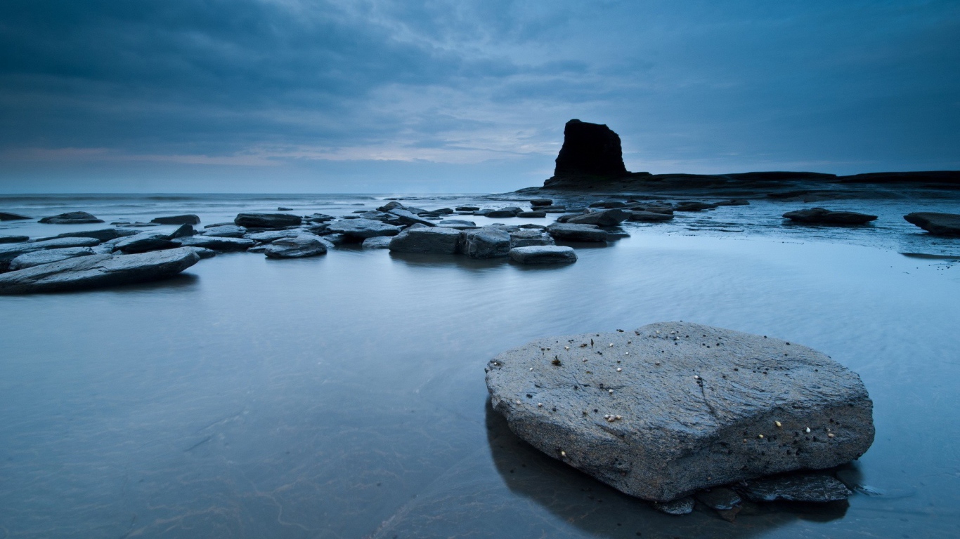 Плоские камни в серой воде у берега