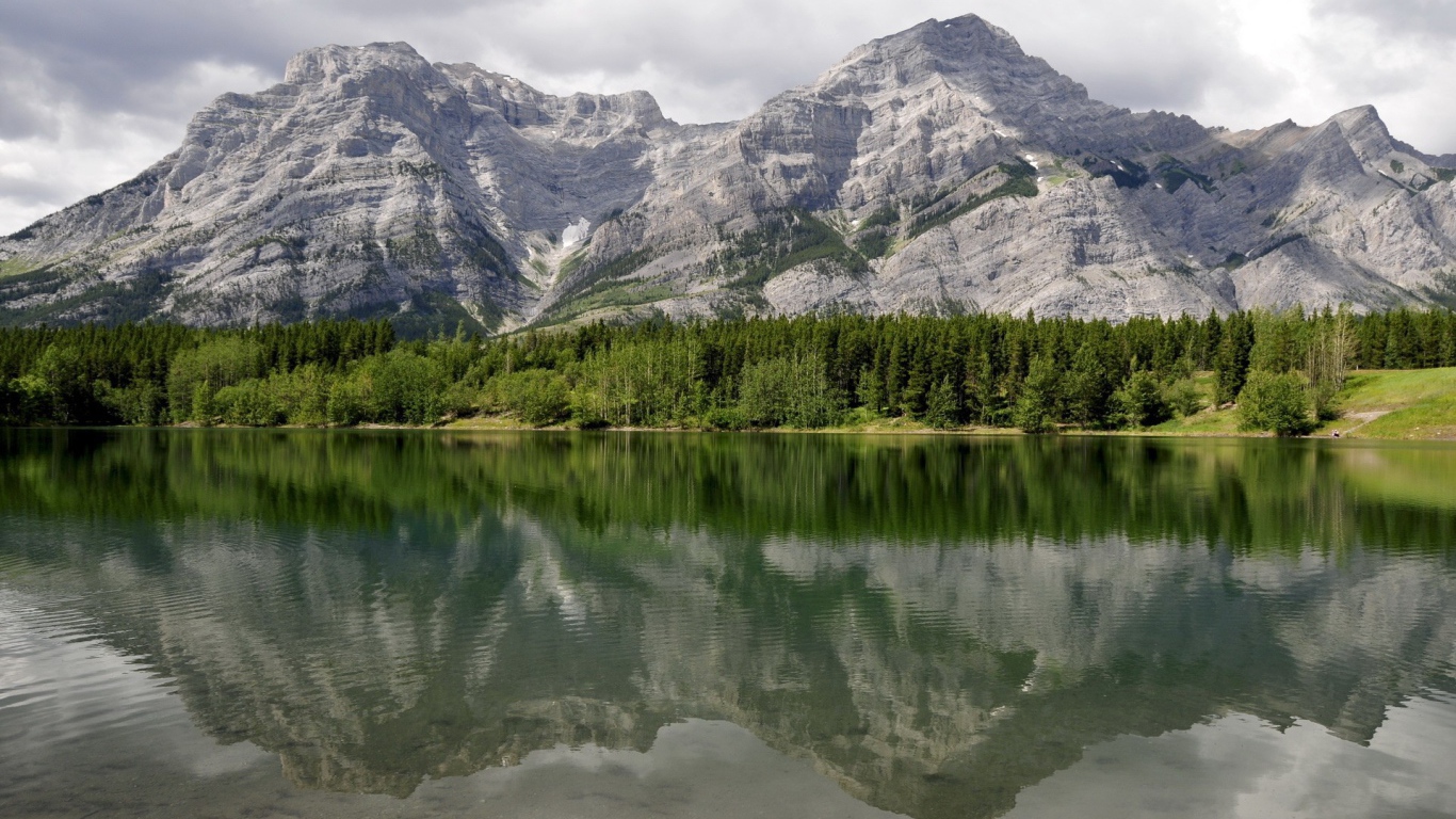 Горы и хвойный лес отражаются в горном озере