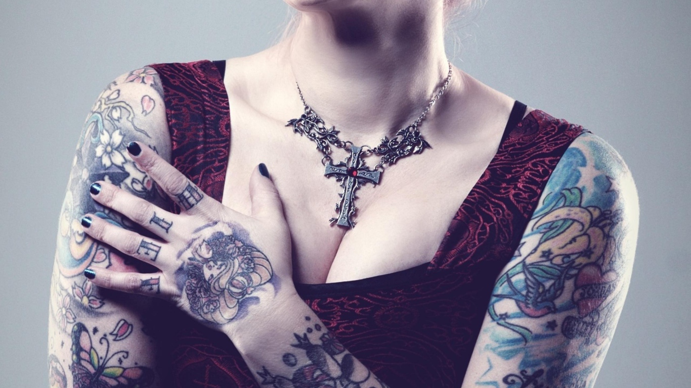 Красивый кулон на груди татуированной девушки