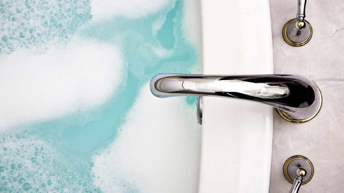 Кран над ванной с голубой водой
