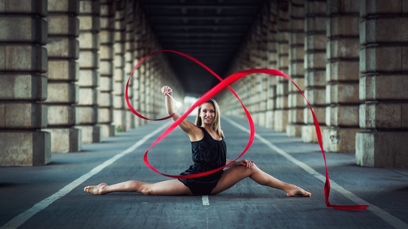 Гимнастка упражняется с красной лентой