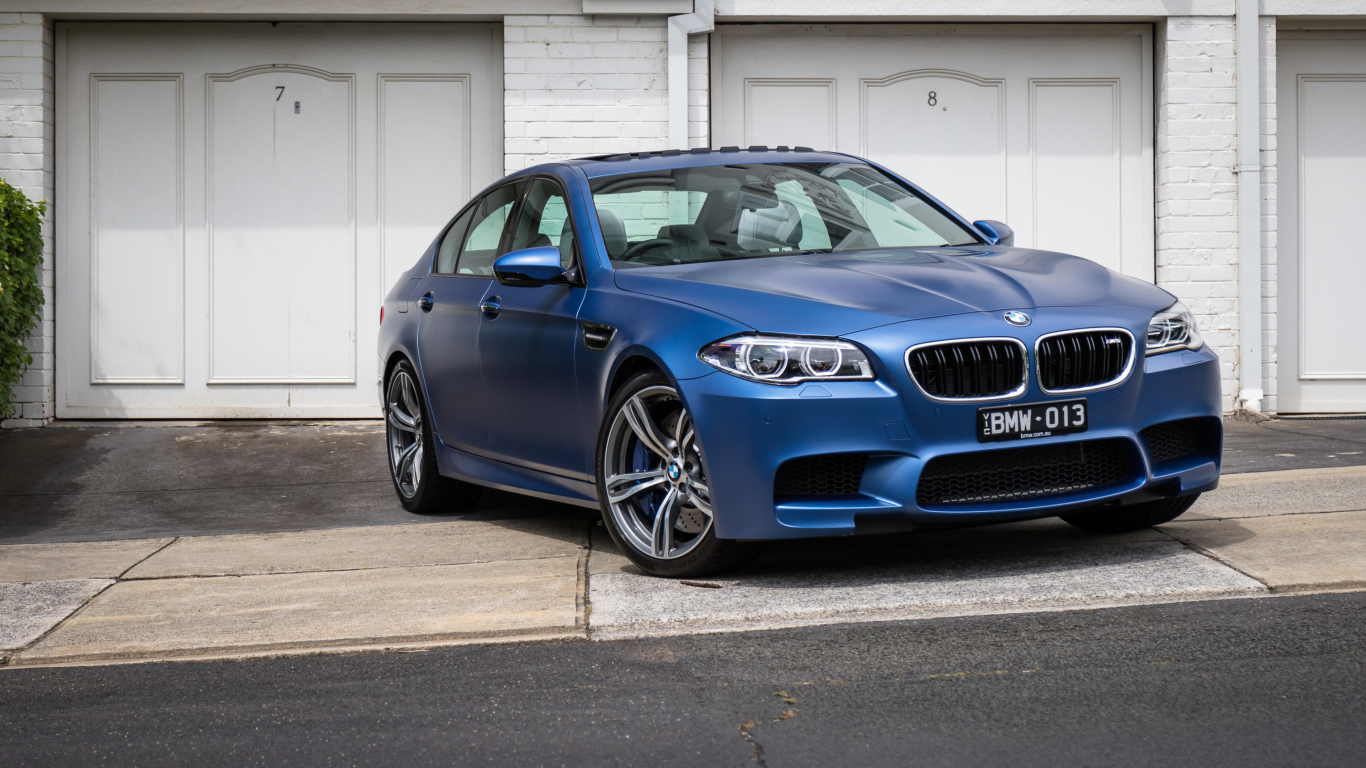 Синий автомобиль BMW 5 Series у гаража