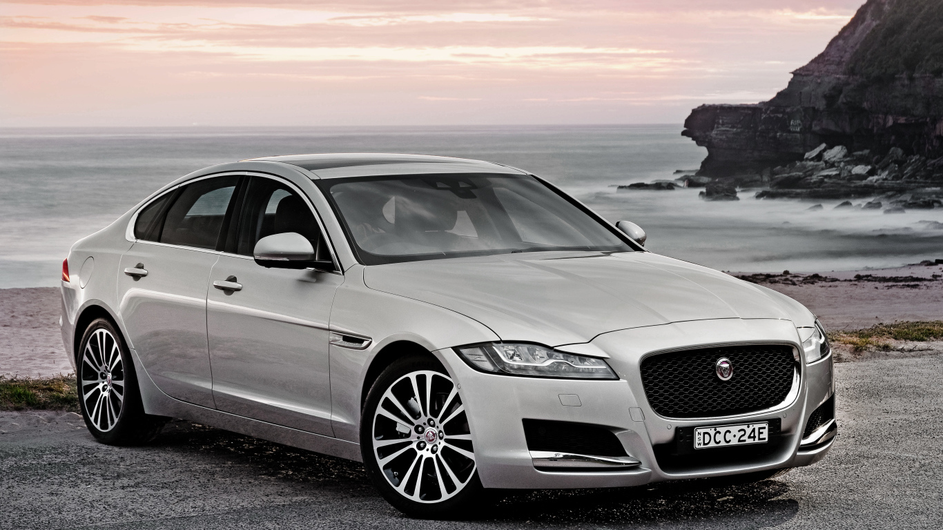 Серебристый автомобиль Jaguar XF на фоне океана