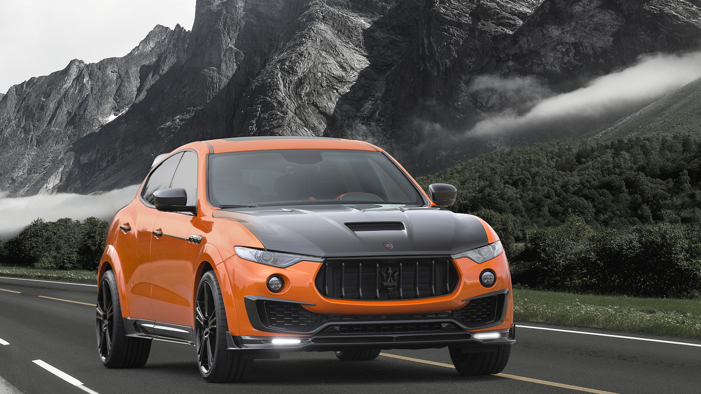 Оранжевый автомобиль Maserati Mansory Levante, 2017 на фоне гор