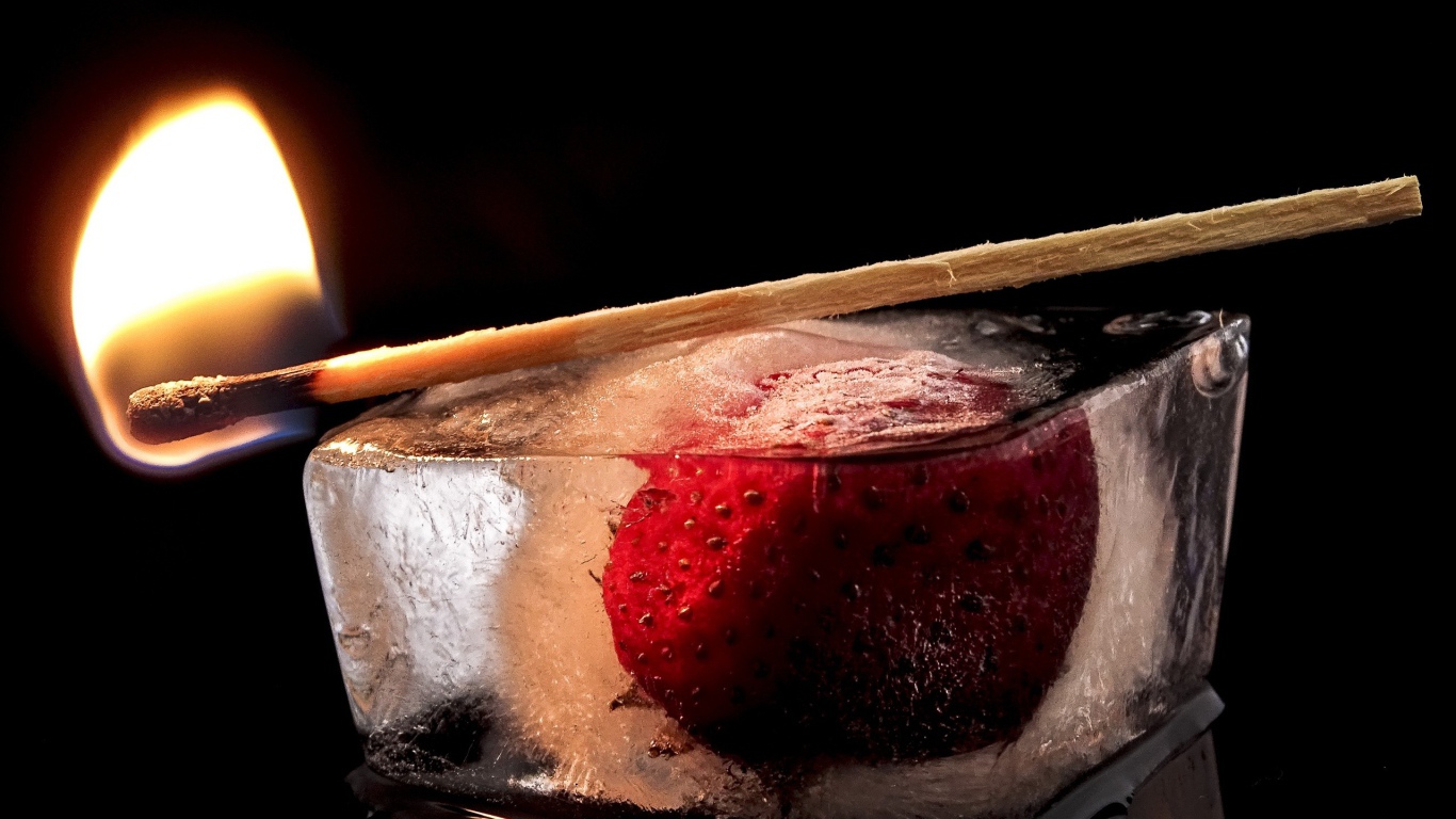Зажженная спичка на кусочке льда с клубникой 