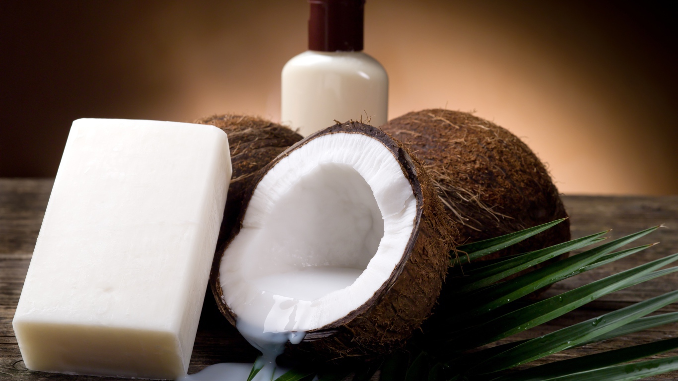 Кокосовое масло с кокосовым мылом и свежими кокосовыми орехами на зеленых листьях