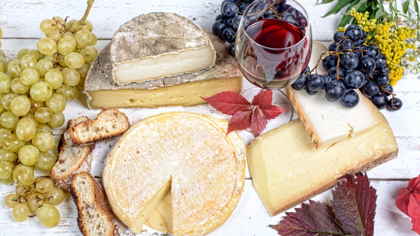 Дорогой сыр с плесенью на столе с виноградом и красным вином